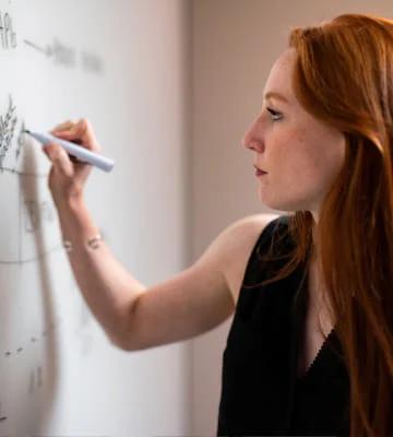 Woman taking notes with marker on whiteboard
