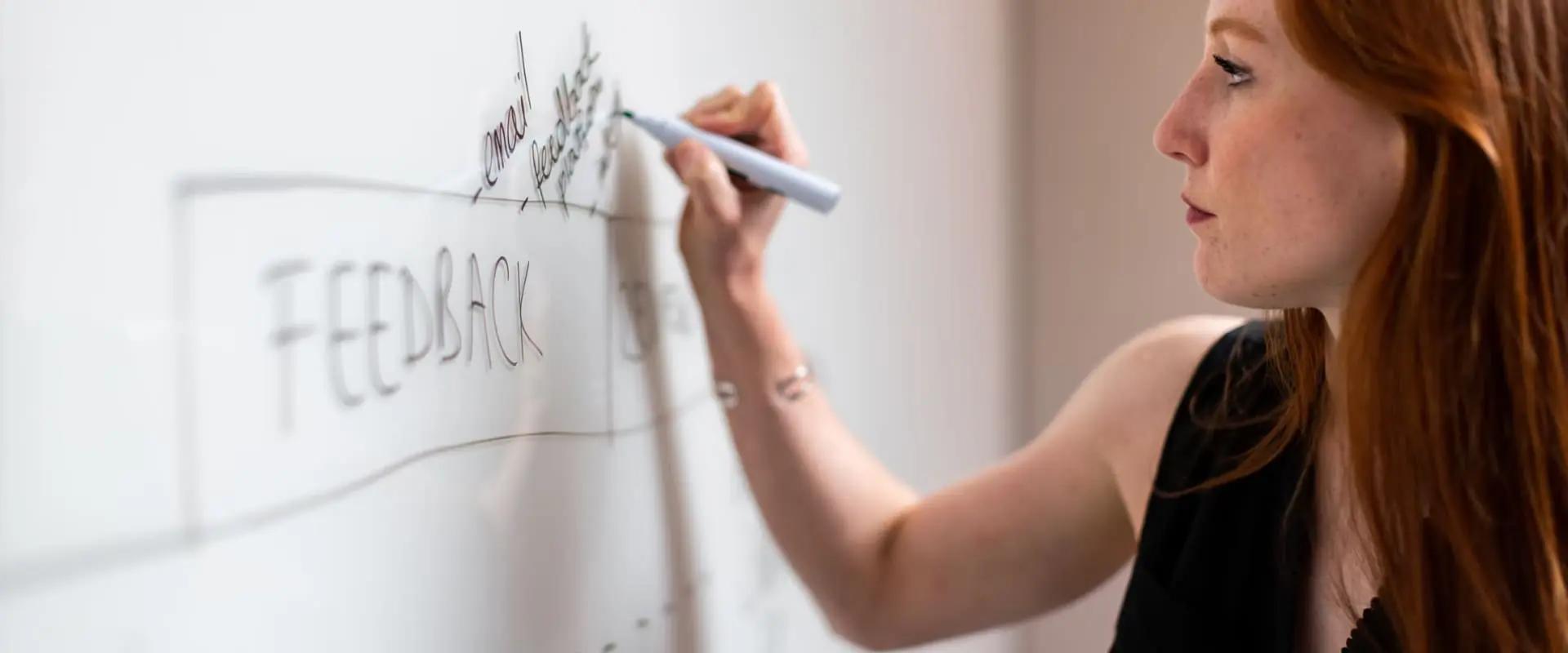 Woman taking notes with marker on whiteboard