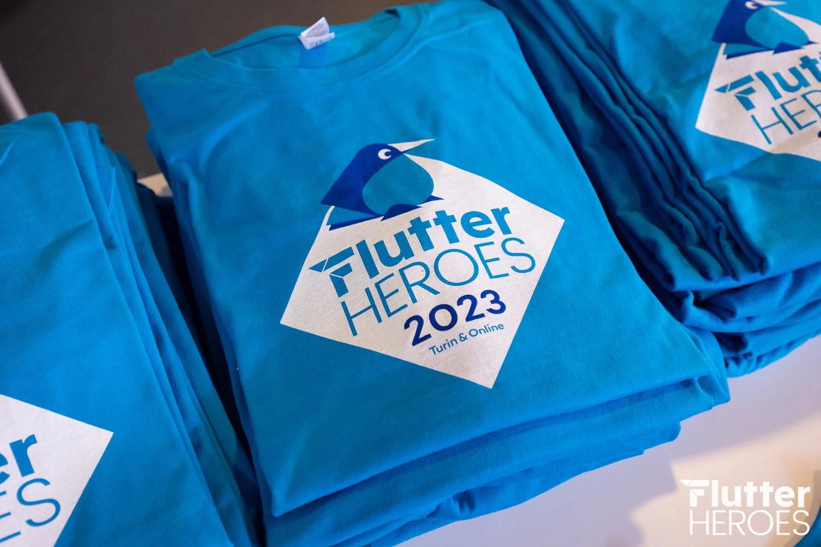Several stacks of blue printed t-shirts, flutter heroes 2023